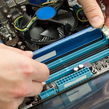 Hands installing RAM into a computer.