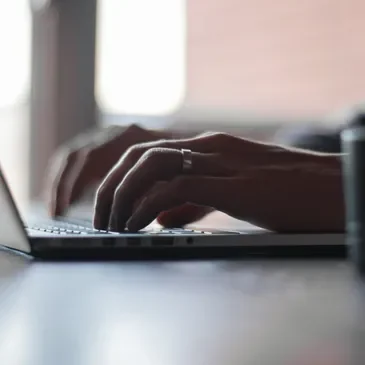 Hands typing on a laptop keyboard.